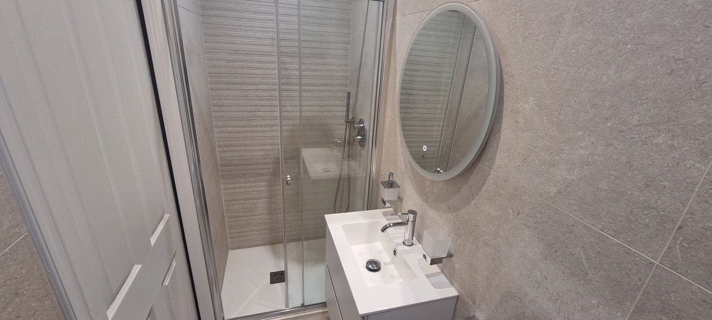 Finished Porcelanosa ensuite with shower enclosure, grey vanity and round mirror