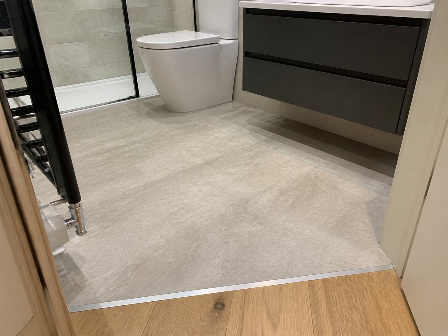 Finished bathroom flooring with neat cuts around fittings